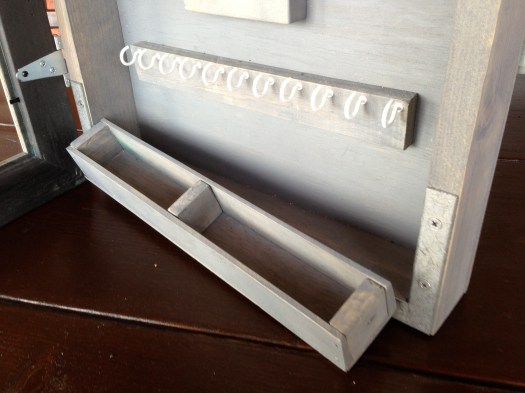 A row of hooks for earrings and a small divided drawer for catching loose jewelry.