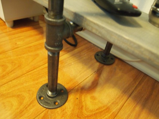 Flange pieces at the bottom give a sturdy base to the legs of the shelf. No real need to screw them into the floor. I started out with felt pads on the bottom, but decided the shelf wasn't going to need them if it never moved.